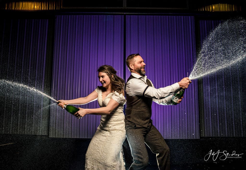 champagne-pop-wedding-exit-candid-couple-celebration-with-fun-champagne-spray-moment